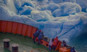 Tourist ship sails close to small iceberg.